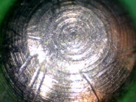 An image of a pin-tumbler pin with marks left by lockpicking tools.